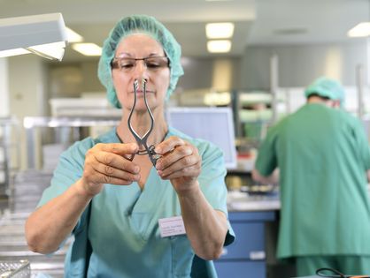 Frau prüft OP-Besteck im Sterilisationsraum